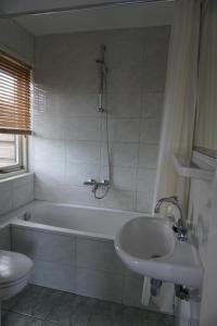un bagno con vasca, lavandino e WC di villa Flore, studio's a Bergen aan Zee