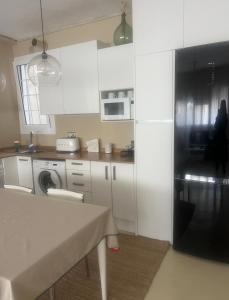 a kitchen with white cabinets and a black refrigerator at Apartamento cerca Playa in Sitges