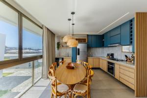 a kitchen with blue cabinets and a wooden table and chairs at Modern and sophisticated apartments near the beach in Maraú – VLL in Marau