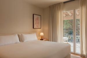 a bedroom with a white bed and a large window at Finca Victoria, a Member of Design Hotels in Begur