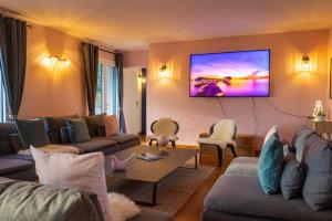 - un salon avec des canapés et une télévision murale dans l'établissement Gîte du Soleil dans la Ruelle - La Grouas, à Étival-lès-Le Mans