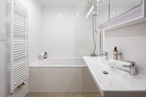 een witte badkamer met een wastafel en een spiegel bij Stylish Flat by the Metro in Praag +27 foto's