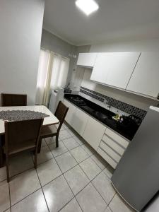 a kitchen with white cabinets and a table with chairs at AP 100m do mar mesma rua do Quiosque VavaZão in Capão da Canoa