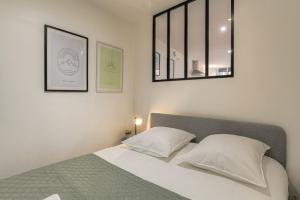 ein Schlafzimmer mit einem Bett mit zwei Kissen und einem Spiegel in der Unterkunft Le Siméon - T2 plein pied, cosy, au cœur de la zone piétonne in Vienne