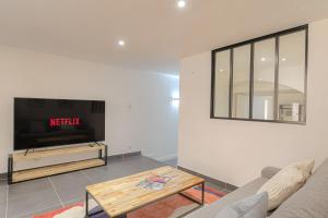 ein Wohnzimmer mit Sofa und Fernseher in der Unterkunft Le Siméon - T2 plein pied, cosy, au cœur de la zone piétonne in Vienne