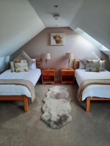 a attic bedroom with two beds and a rug at A Stylish Country Retreat! in Keilour