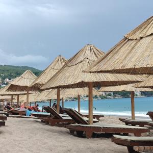 a group of straw umbrellas on a beach at Holiday home Sutomore in Sutomore +35 photos