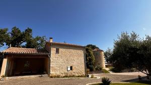 an old stone house with a tower in the background at Domaine Léa Chanflaur - Spa - La maison du bonheur in Terraube