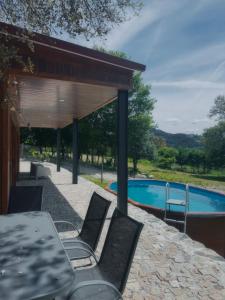eine Terrasse mit Tisch und Stühlen neben einem Pool in der Unterkunft Casa do Esquilo in Cabeceiras de Basto