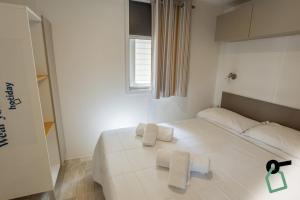 a white bedroom with a bed with towels on it at HOTIDAY Lodge Orbetello in Orbetello