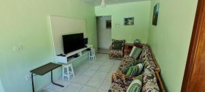 a living room with a couch and a television at Encantadora Chácara com Piscina em Itanhaém in Itanhaém