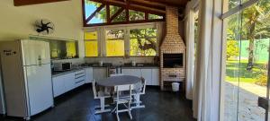 a kitchen with a table and a white refrigerator at Encantadora Chácara com Piscina em Itanhaém in Itanhaém
