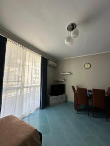a bedroom with a living room with a table and a clock at Eri Apartments 4 in Shëngjin