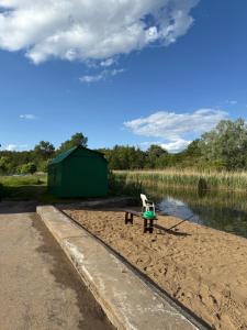 Un banco sentado en la arena junto a un lago en Sypialnia Rybaka, en Chwarszczany