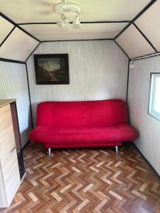 un sofá rojo sentado en una esquina de una habitación en Sypialnia Rybaka, en Chwarszczany