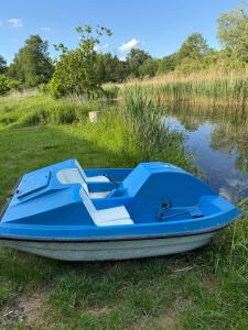 un barco azul sentado en el césped junto al agua en Sypialnia Rybaka, en Chwarszczany