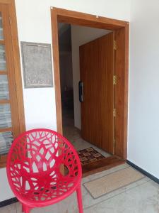 a red chair sitting in front of a door at La-Casona in Kottayam +6 photos
