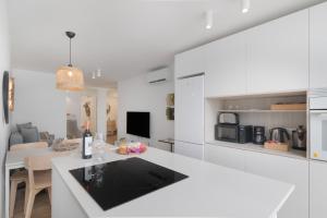 een witte keuken met een wit aanrecht en een eetkamer bij Chez Oti Puerto Rico in Puerto Rico de Gran Canaria