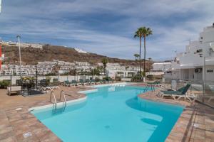 een groot zwembad met stoelen en palmbomen bij Chez Oti Puerto Rico in Puerto Rico de Gran Canaria
