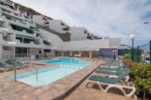 een zwembad met ligstoelen voor een gebouw bij Chez Oti Puerto Rico in Puerto Rico de Gran Canaria