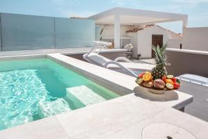 a swimming pool with a bowl of fruit next to a house at Aquarius Deluxe Apartments in Santa Teresa Gallura