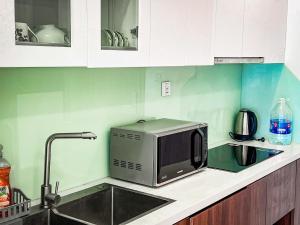 eine Küchentheke mit Mikrowelle und Spüle in der Unterkunft Hoci Homestay Vinhomes Ocean Park in Gia Lâm Pho