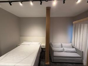 ein kleines Schlafzimmer mit einem Bett und einer Couch in der Unterkunft Canal 3 lado da praia e R da Paz in Santos