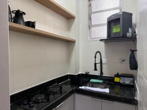 eine Küche mit Spüle und Mikrowelle in der Unterkunft Canal 3 lado da praia e R da Paz in Santos + 13 Fotos