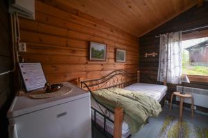una piccola camera da letto con un letto in una cabina di legno di Hännilänsalmi Camping a Viitasaari