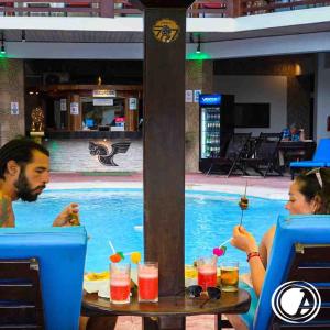 two people sitting at a table in front of a swimming pool at Aryia Máncora in Máncora