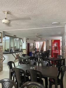 a restaurant with tables and chairs and a coke machine at HOTEL LOS GUADUALES in Barranquilla