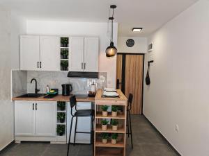a kitchen with white cabinets and a counter with a table at Apartman Holiday 3 - Srebrno jezero in Veliko Gradište