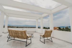 un porche blanco con 2 sillas y una mesa en Areti White Villas - Villa 1, en Loutraki