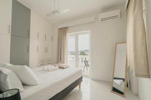 a white bedroom with a large bed and a window at Areti White Villas in Loutraki +40 photos