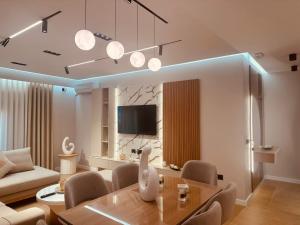 a living room with a dining table and a tv at Vasili Apartament in Gjirokastër