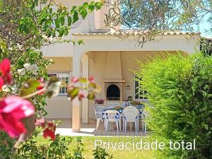 a patio with a table and chairs and a fireplace at Casa das Oliveiras - piscina privada, jardim, perto da praia in Moncarapacho
