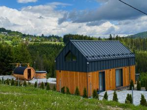 a wooden cabin with a black roof in a field at Młynarska Dolina A in Koniaków