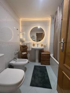 Un baño con inodoro, lavabo y espejo. en NS GuestHouse, en Armação de Pêra
