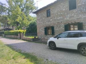 a white car parked in front of a stone house at Home in Tuscany in Greve in Chianti +14 photos