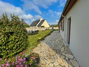 a stone walkway next to a building with a hedge at Ti maeronez in Paimpol