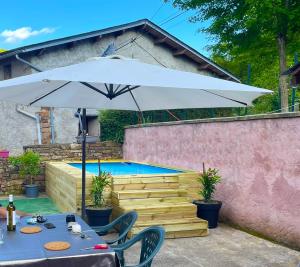 a table with an umbrella next to a swimming pool at L'Auselon de montanha in Laval-Roquecézière