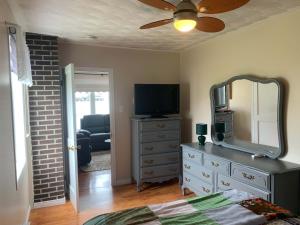 a bedroom with a dresser with a mirror and a television at Long Beach Lookout Vacation Rental in Twillingate +3 photos