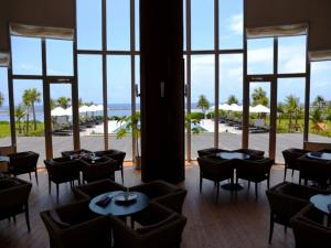 ein Restaurant mit Tischen und Stühlen und Meerblick in der Unterkunft Cypress Resort Kumejima in Kumejima