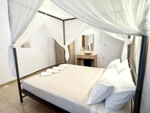 a bedroom with a white canopy bed with white pillows at Pachia Ammos Falasarna in Falasarna