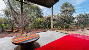 a room with a hammock and a red carpet at Refúgio do Boto, casa nova em meio a natureza rústica in Alto Paraíso de Goiás