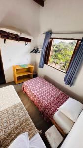 a room with two beds and a window at Refúgio do Boto, casa nova em meio a natureza rústica in Alto Paraíso de Goiás