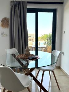 a glass dining table and white chairs in a room at Pachia Ammos Falasarna in Falasarna