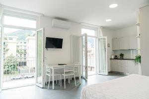 a white bedroom with a table and a kitchen with a balcony at Casa LiLu by Comorooms in Como
