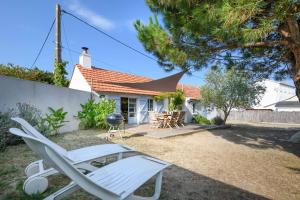 a yard with a chair and a grill and a house at Charmante maison vendéenne proche de la plage in Notre-Dame-de-Monts