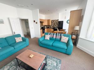 a living room with two blue couches and a table at Private Parking, Central Llandudno, King Bed with Ensuite at Clement Lodge in Llandudno